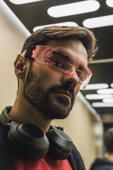 Man with wireless headphones wearing futuristic smart glasses