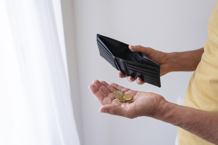 Hands of man holding wallet and coins at home