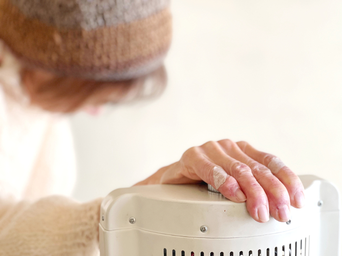 Elderly woman nodding off with her hand on an electrical appliance