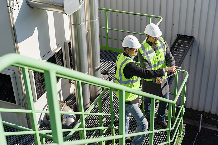Engineer with colleague gesturing and discussing at recycling plant