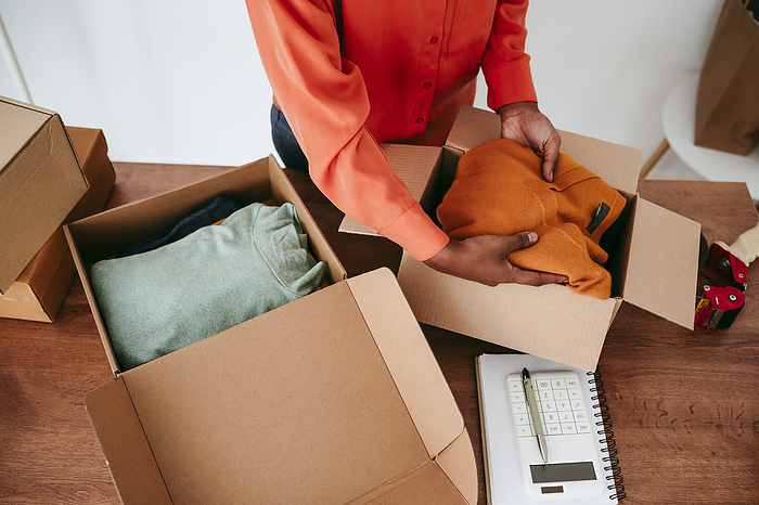 Hands of businesswoman packing orders in box at desk