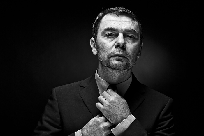 Portrait of mature man adjusting tie, close up