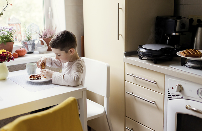 Boy having breakfast on dining table in kitchen
