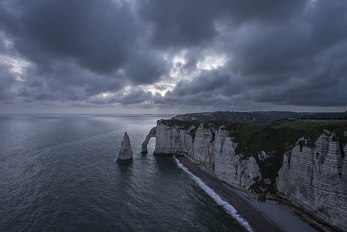 France, Normandy, Etretat, Falaise dAval cliffs and Aiguille dEtretat sea stack at cloudy dusk
