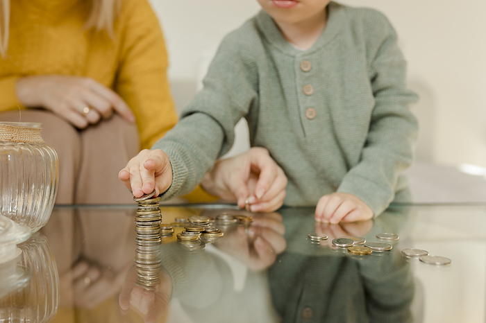 Mother with son counting coins on table at home