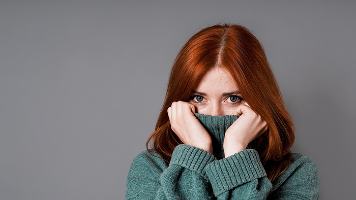 shy or embarrassed woman pulling turtleneck sweater over face shy or embarrassed woman pulling turtleneck sweater over face, Photo by Zoonar Axel Bueckert