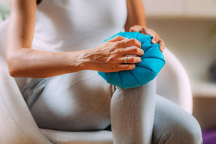 Woman holding a cold compress to her knee Woman holding a cold compress over her painful knee., by MICROGEN IMAGES SCIENCE PHOTO LIBRARY