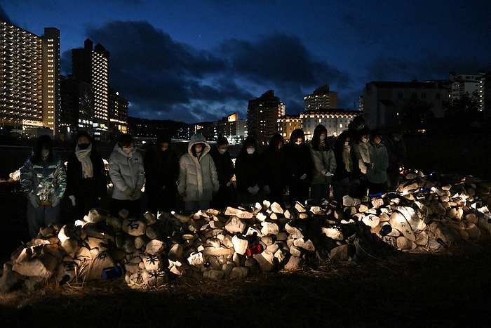 People observe a moment of silence in front of a mound of stones in the shape of the Chinese character for  life  before the 28th anniversary of the Great Hanshin Earthquake. People observe a moment of silence in front of a stone pile in the shape of the character for  life  before the 28th anniversary of the Great Hanshin Earthquake in Takarazuka, Hyogo Prefecture.