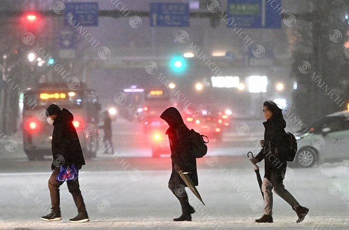 Intense Cold Wave in the Japanese Archipelago People walk at a pedestrian crossing in front of JR Niigata Station amid strong winds and blowing snow at 6:23 p.m. on January 24, 2023 in Chuo ku, Niigata City  photo by Nishi Natsuo.