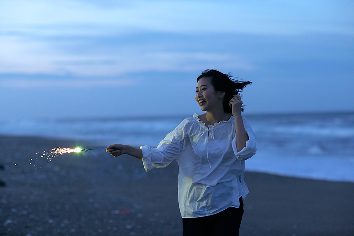 Japanese woman setting off fireworks on the beach