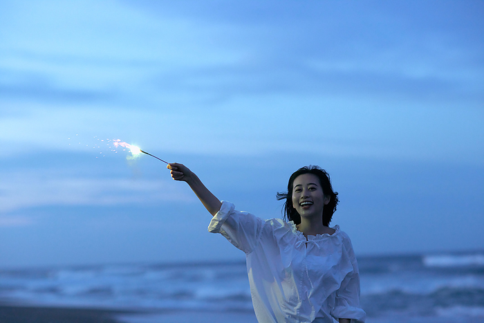 Japanese woman setting off fireworks on the beach
