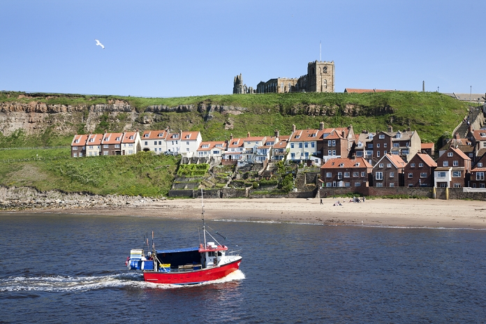 United Kingdom Fishing boat entering the harbour below Whitby Abbey, Whitby, North Yorkshire, Yorkshire, England, United Kingdom, Europe