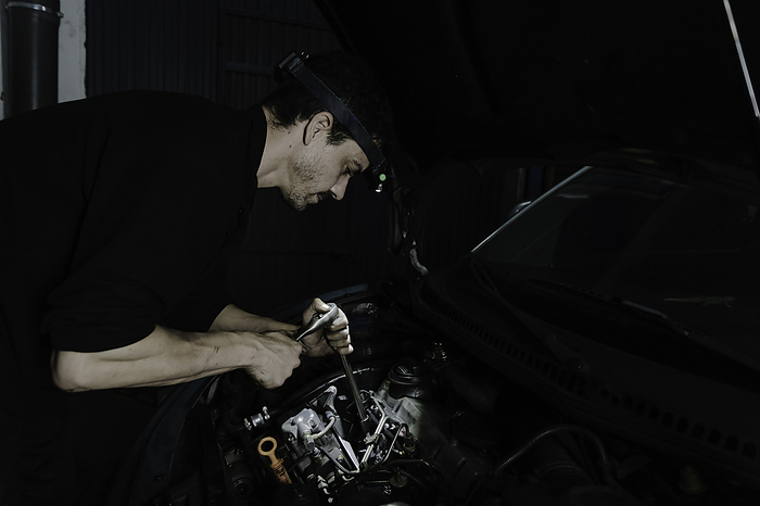 Repairman fixing engine of car in workshop