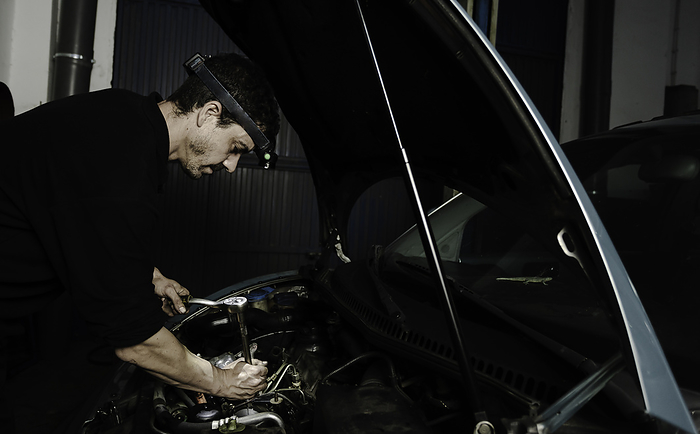 Repairman fixing engine of car in workshop