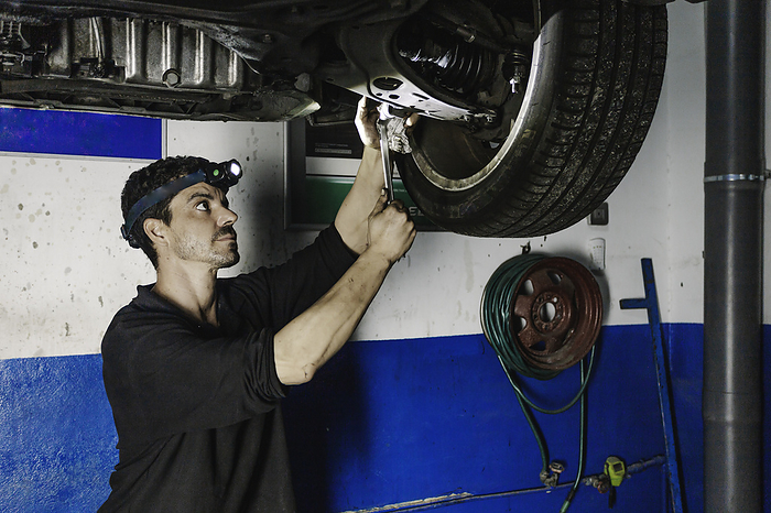 Repairman installing car wheel in workshop