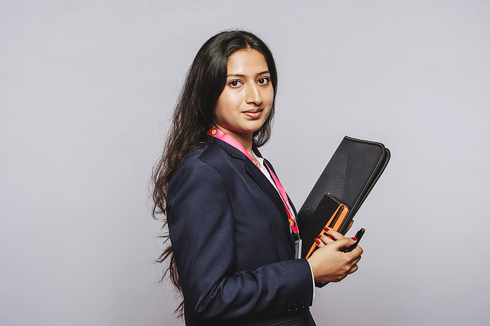 beautiful indian millennial girl holding book in grey background