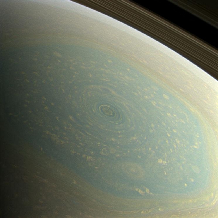 Giant Vortex  at Saturn s North Pole Observed by Cassini spacecraft  The north pole of Saturn, in the fresh light of spring, is revealed in this color image from NASA s Cassini spacecraft. The north pole was previously hidden from the gaze of Cassini s imaging cameras because it was winter in the northern hemisphere when the spacecraft arrived at the Saturn system in 2004. A hurricane like storm circling Saturn s north pole at about 89 degrees north latitude is inside the famous  hexagon  feature, which scientists think is a wandering jet stream that whips around the north pole at about 220 miles per hour  98 meters per second . It folds into a six sided shape because the hexagon is a stationary wave that guides the path of the gas in the jet. The hexagon borders occur at about 77 degrees north latitude and the feature is wider than two Earths. Saturn s rings can be seen at the upper right of the image. Images with red, green and blue spectral filters were combined to create this natural color view, which is what the human eye would see if we were there at Saturn. The image here was acquired with the Cassini spacecraft wide angle camera on Nov. 27, 2012 at a distance of approximately 260,000 miles  418,000 kilometers  from Saturn and at a sun Saturn spacecraft, or phase, angle of 96 degrees. Image scale is 18 miles  28.6 kilometers  per pixel.  Photo by NASA JPL Caltech SSI 