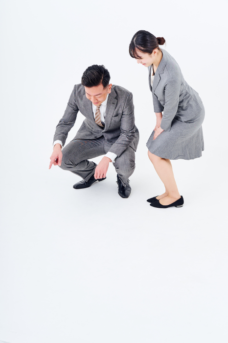 Japanese man and woman in suits staring at the bottom of the screen (People)
