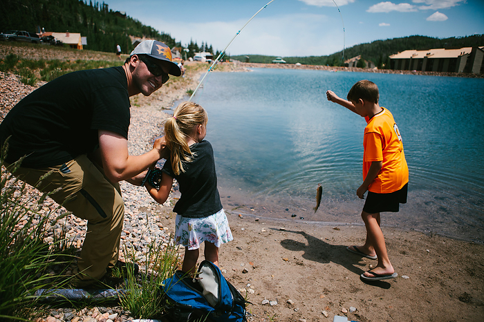 Family catches fish on vacation lakeside in the mountains