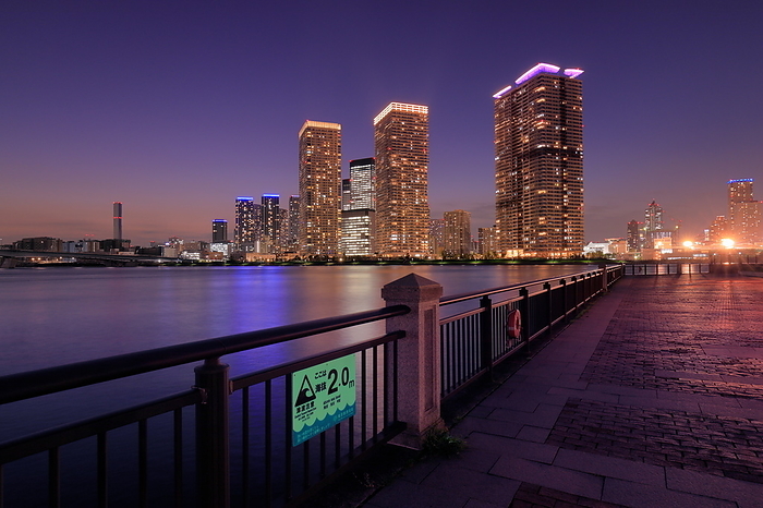 Night view of Harumi towers and waterfront tsunami warning board, Tokyo