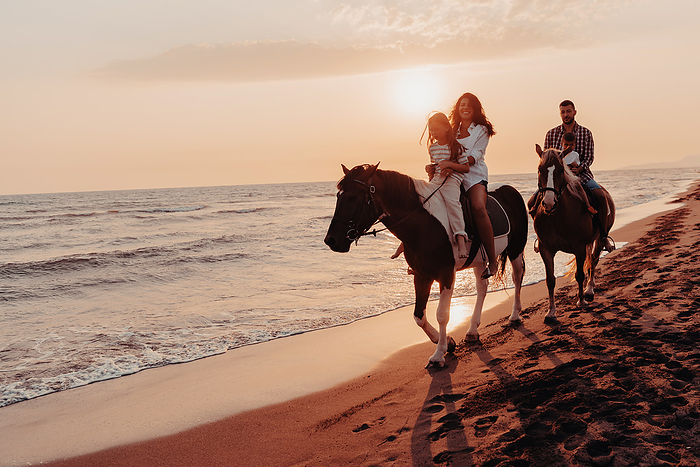 The family spends time with their children while riding horses together on a sandy beach. Selective focus The family spends time with their children while riding horses together on a sandy beach. Selective focus. High quality photo, by BENIS ARAPOVIC