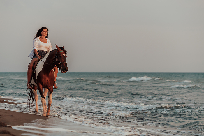 Woman in summer clothes enjoys riding a horse on a beautiful sandy beach at sunset. Selective focus A woman in summer clothes enjoys riding a horse on a beautiful sandy beach at sunset. Selective focus. High quality photo, by BENIS ARAPOVIC