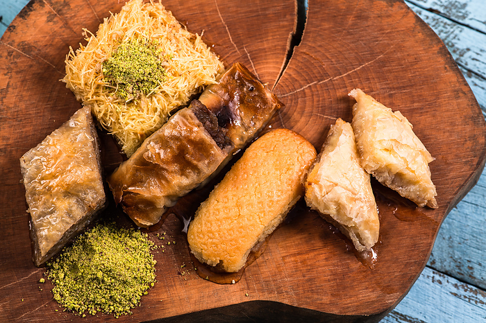 Ramadan Kareem, traditional Turkish middle eastern Iftar sweets Baklava with pistachios and fresh honey on rustic wooden plate and vintage blue background table. Top view. Ramadan Kareem, traditional Turkish middle eastern Iftar sweets Baklava with pistachios and fresh honey on rustic wooden plate and vintage blue background table. Top view. High quality photo