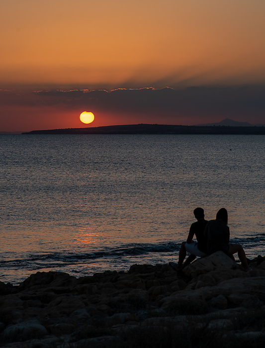 Silhouette of young couple enjoying beautiful sunset at the beach. Silhouette of young couple enjoying beautiful sunset at the beach. Romantic moment human relationship