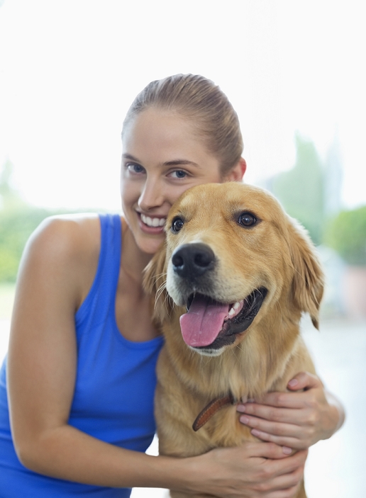 Smiling woman hugging dog indoors