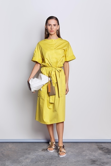 Full length portrait of cute fashion model in yellow dress with handbag
