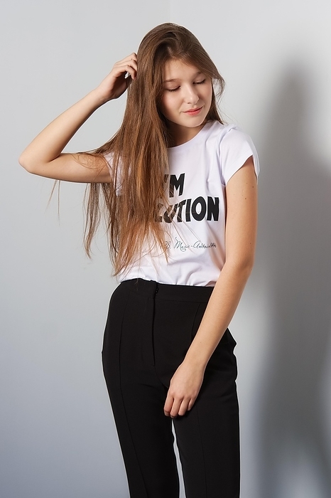 Attractive fashion model in pants and t-shirt with inscription touching her hair