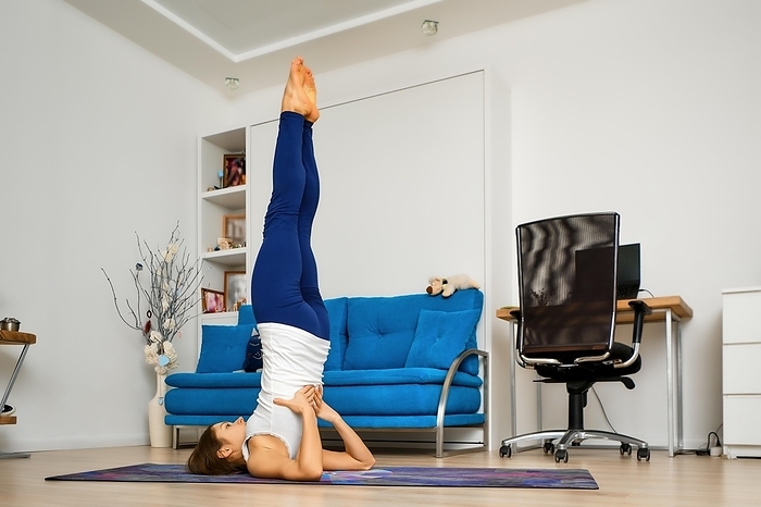 Young woman does supported shoulderstand yoga pose