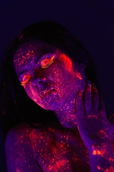 Portrait of beautiful woman with ultraviolet paint on her face. Girl with neon make up in ultraviolet light