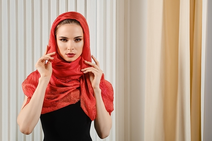 Classy woman in red silk headscarf wrapped around her head and piercing gaze
