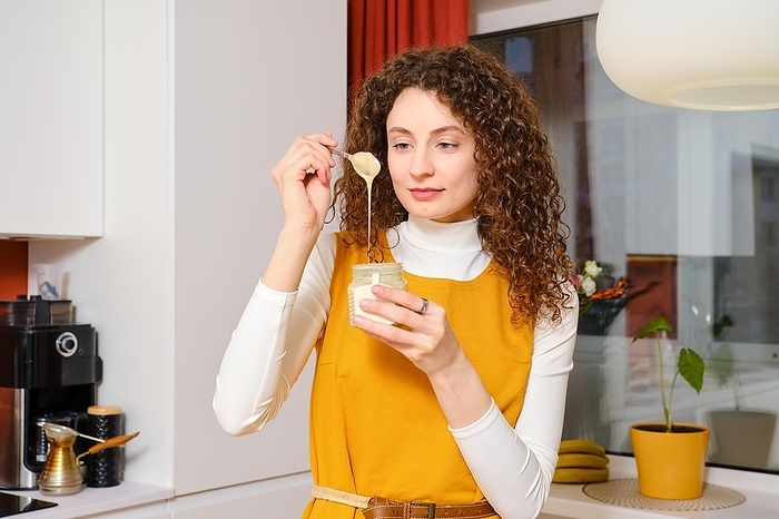 Young woman examining texture and consistency of sesame seed paste urbech