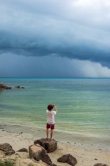 Young man standing on the beach, tropical storm, storm, thunderstorm on the beach, Mae Nam Beach, Ko Samui Island, Thailand, Asia