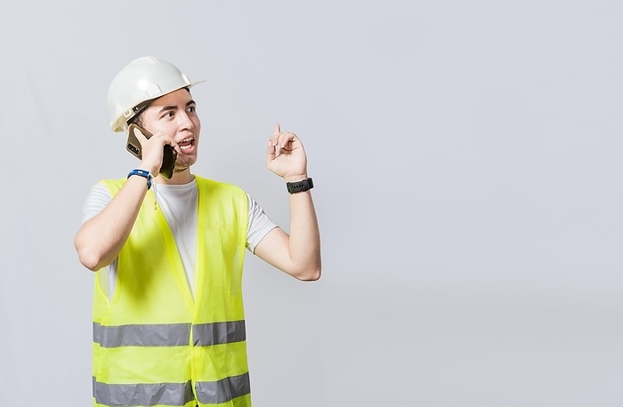Builder engineer in vest talking on cell phone isolated. Civil engineer concept talking on cellphone isolated, Smiling engineer talking on the phone isolated with copy space