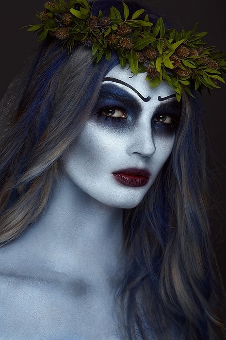 Portrait of a horrible scary Corpse Bride in wreath with dead flowers, halloween makeup and long manicure.Design of nails.Photo taken in studio
