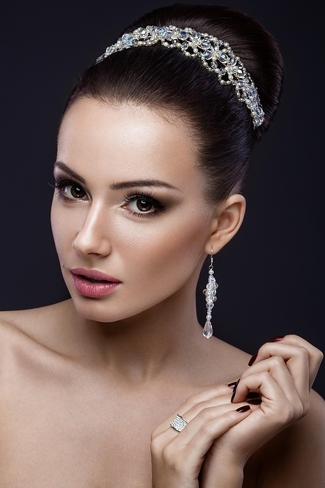 Beautiful brunette girl with perfect skin, evening make-up, wedding hairstyle and accessories.Beauty face. Picture taken in the studio