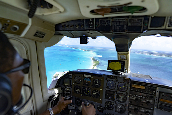 Antigua and Barbuda Pilot in the cockpit of small twin engined aircraft admiring the idyllic landscape flying over the turquoise Caribbean Sea. Photo by: Roberto Moiola