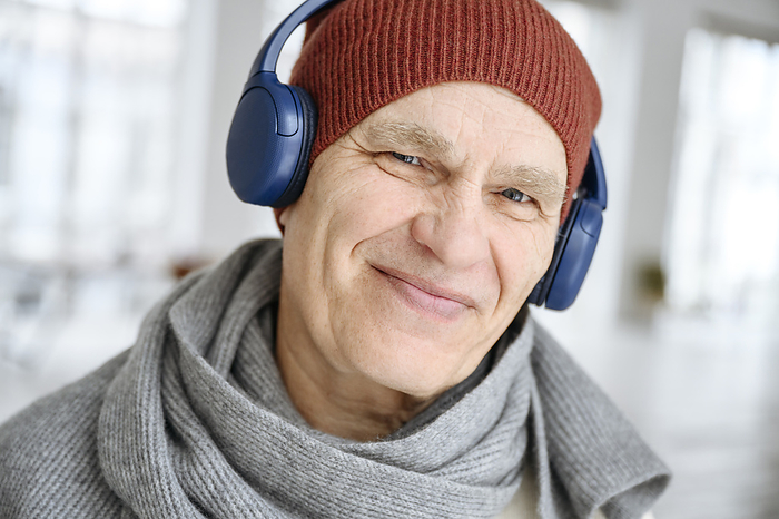 Happy man wearing knit hat listening to music through headphones