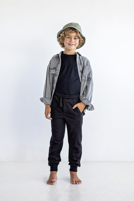 Smiling boy with hand in pocket standing against white background