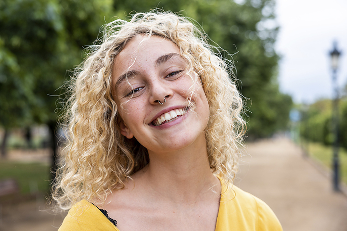 Happy young woman with blond hair in park