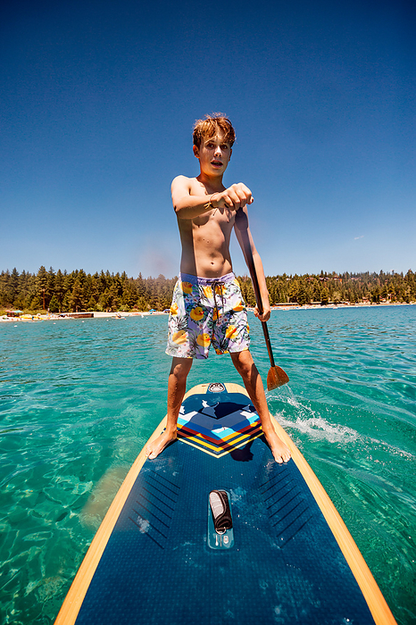 USA, California, Boy paddleboarding on Lake Tahoe