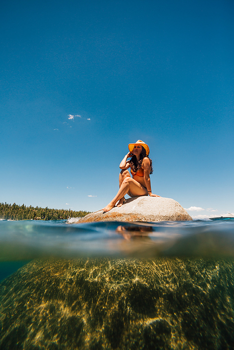 USA, California, Woman relaxing on boulder in Lake Tahoe