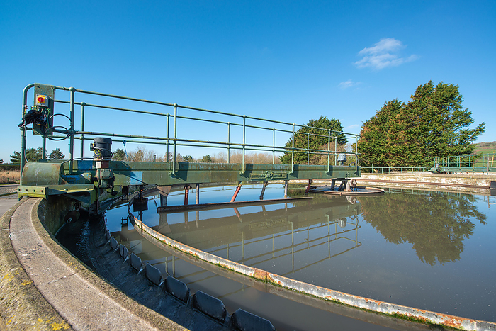 Settlement tank at a sewage treatment works Settlement tank with a weir. In wastewater treatment, weirs are walls that control the flow of water into launders  sloped channels surrounding the tank . Weirs usually have notches, holes or slits alongside their length to enable a uniform flow rate., by ANDY DAVIES SCIENCE PHOTO LIBRARY