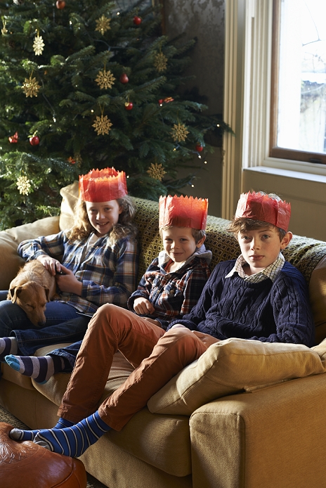 Children in paper crowns sitting on sofa