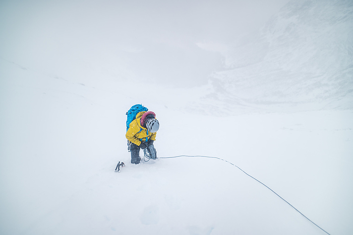 Male mountaineer climbing in white out snowy conditions Male mountaineer climbing in white out snowy conditions