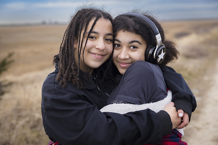 portrait of biracial sisters embracing and smiling
