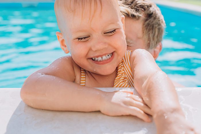 Close-up of a laughing Caucasian child in an outdoor swimming pool